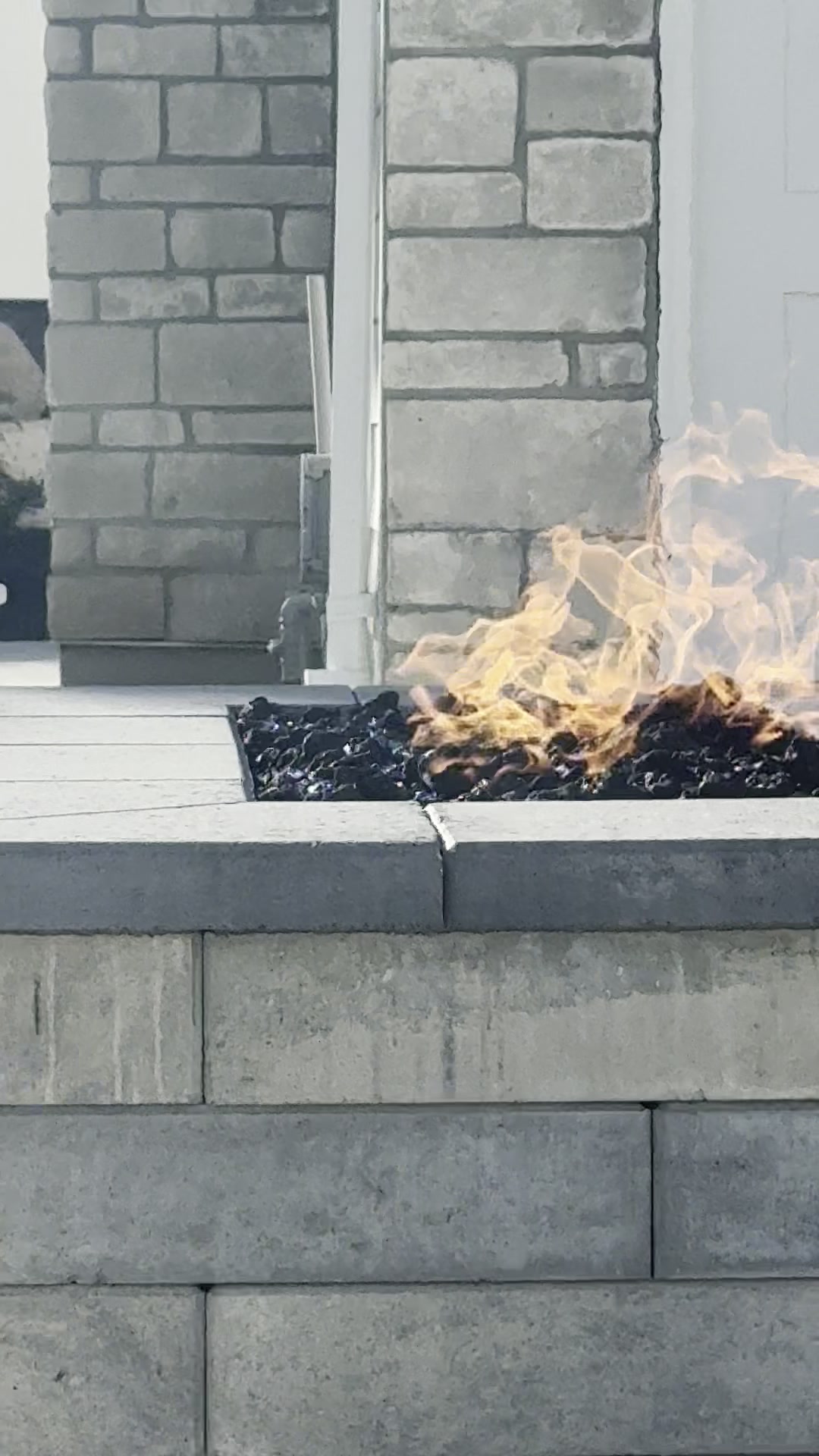 Built-in fire feature with active flames, lava rocks, and stacked stone columns
