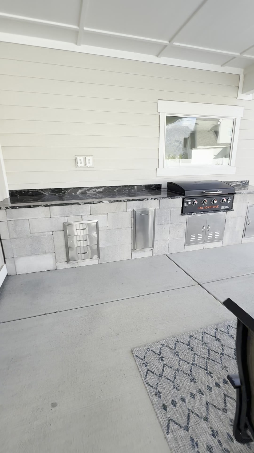 Outdoor kitchen with Blackstone grill, stone facing, and marble counter