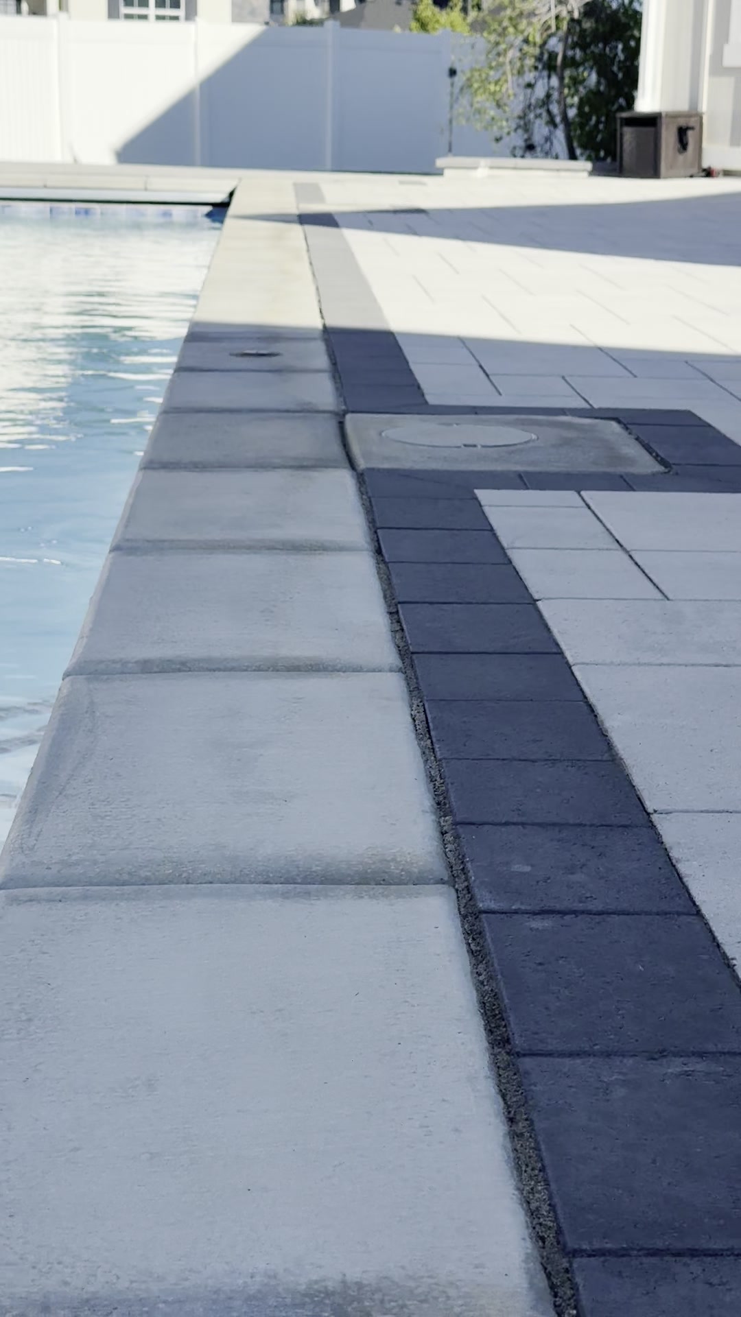 Pool deck coping detail with paver edge and contrasting dark accent band